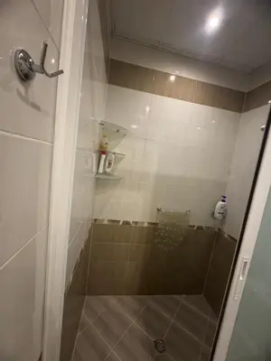 a shower with a glass door in a bathroom at Лукс апартамент Базилика отделен вход in Sandanski