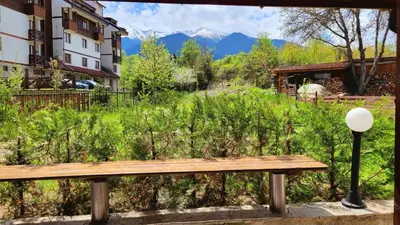 a wooden bench sitting in front of a field with mountains at Spacious stylish studio with large terrace and amazing view, 5 min to Gondola & Bar Str in Bansko