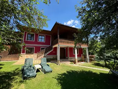 a red house with two lawn chairs in front of it at Borimechkova Kashta in Koprivshtitsa