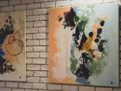 two paintings hanging on a brick wall at Stylish 1BD - Free Private Garage in Plovdiv