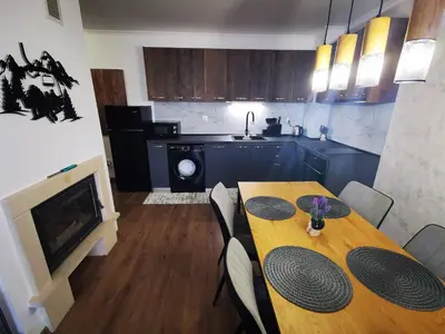 a dining room with a table and a kitchen at Viva 3 Grand monastery in Pamporovo