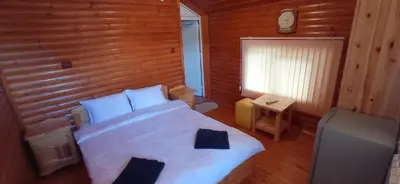 a bedroom with a white bed with a wooden wall at Къща за гости Джамбазови in Sarnitsa