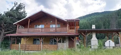 a large wooden house with a large deck at Къща за гости Джамбазови in Sarnitsa