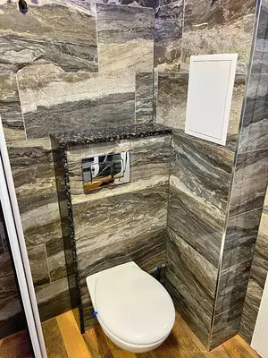 a bathroom with a toilet and a stone wall at Azurro Residence in Sofia