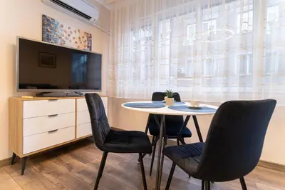 a dining room with a table and chairs and a tv at Heart of the City 2-Bedroom Apartment in Plovdiv