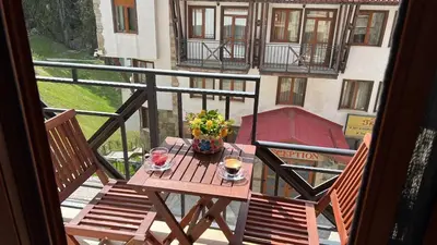 a balcony with a table and two chairs on a balcony at Апартамент Касъл in Pamporovo