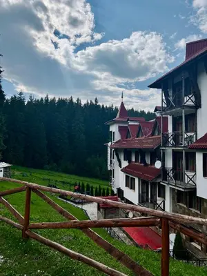 a fence in front of a building in a field at Апартамент Касъл in Pamporovo