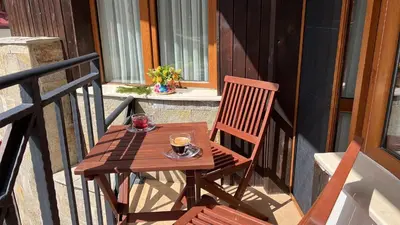 a wooden table on a balcony with a cup of coffee at Апартамент Касъл in Pamporovo