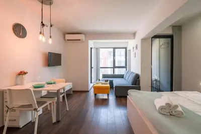a room with a bed and a table and a couch at Bright Studio in the City Center in Sofia