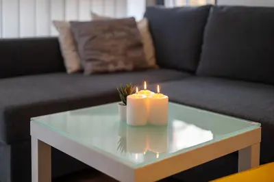 two candles on a glass table in front of a couch at Bright Studio in the City Center in Sofia