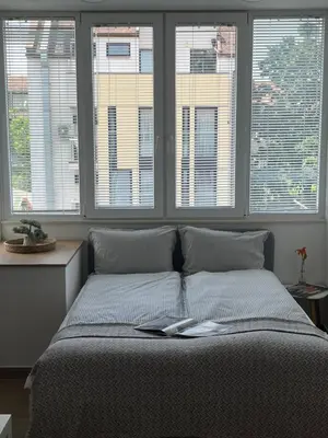 a bed with a book on it in a room with windows at Bunaya Sofia in Sofia