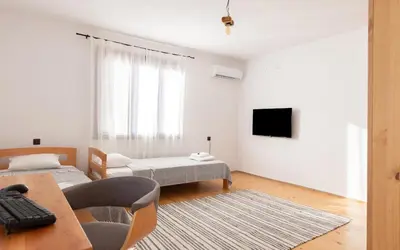 a white living room with a table and a tv at Къща за гости Константин и Елена - гр. Девин in Devin