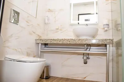 a white bathroom with a sink and a toilet at Hotel Forum City in Pazardzhik