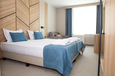 a bedroom with a large bed with blue pillows at Hotel Forum City in Pazardzhik