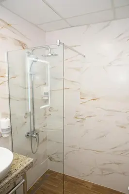 a bathroom with a glass shower with a sink at Hotel Forum City in Pazardzhik
