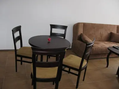 a table and chairs in a living room with a couch at Krasi Apartments in Zornitsa Complex in Stoykite