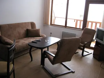 a living room with a couch and a table and chairs at Krasi Apartments in Zornitsa Complex in Stoykite