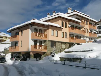 a apartment building in the snow with snow covered grounds at Krasi Apartments in Zornitsa Complex in Stoykite