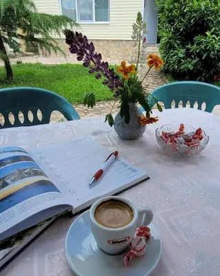 a cup of coffee and a book on a table with a cup of coffee at Вила Виктория in Chekhlare