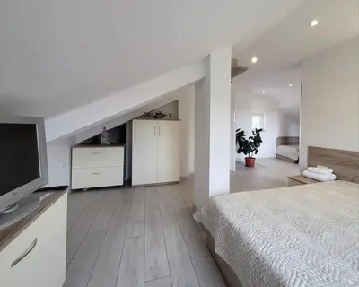 a white bedroom with a bed and a television at Вила Виктория in Chekhlare