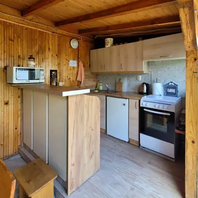a kitchen with wooden cabinets and a stove top oven at Вила Виктория in Chekhlare