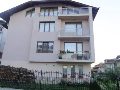 a tall white building with a fence in front of it at Апартамент Радост in Bansko