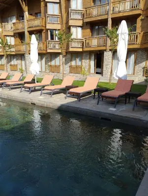 a row of chairs with umbrellas next to a body of water at Pirin Golf - NIRVANA, Studio&SPA in Razlog