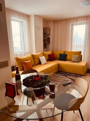 a living room with a yellow couch and a glass table at Grand resort luxury apartment in Pamporovo