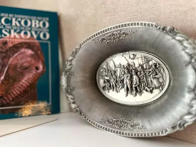 a silver plate with a picture of a dinosaur and a book at Central Sofia Condo in Sofia