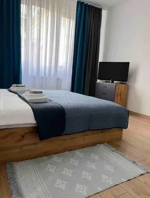 a bedroom with a bed with blue curtains and a television at Modern City Center 2 Bedroom Apartment in Sofia