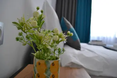 a vase with flowers on a table next to a bed at Modern City Center 2 Bedroom Apartment in Sofia