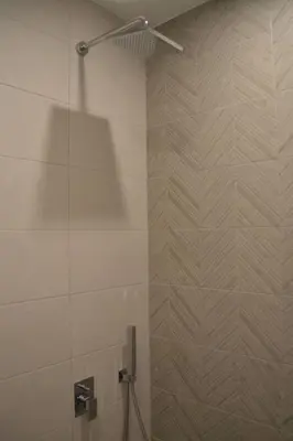 a bathroom with a shower with a tile wall at Modern City Center 2 Bedroom Apartment in Sofia