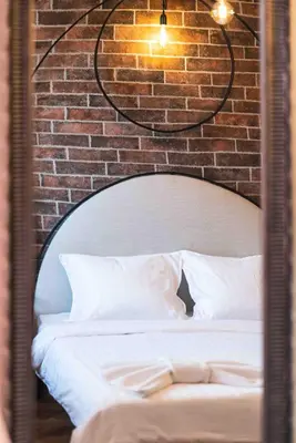 a mirror reflecting a bed with a brick wall at Heart of the Center, 2Bedroom View Lux Apartment in Sofia