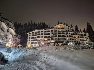 a large building in the snow at night at Elit Pamporovo Accommodation in Pamporovo