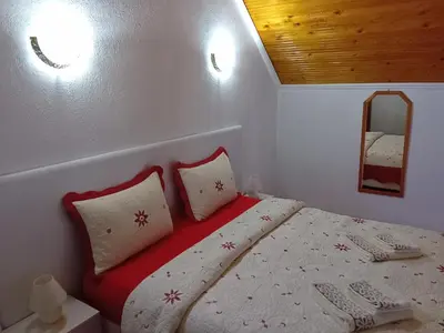 a bedroom with a bed with two pillows and a mirror at Апартамент Стела in Sofia
