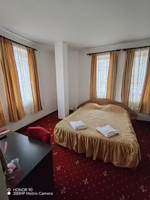 a bedroom with a bed with a table and windows at Парк - Хотел Макензен in Melnik