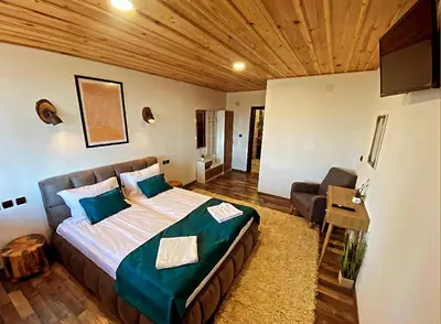 a bedroom with a large bed and a chair in it at Rooms in Leshten in Leshten