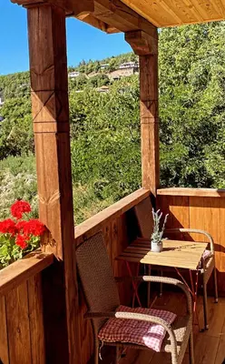 a wooden porch with a table and chairs and flowers at Rooms in Leshten in Leshten