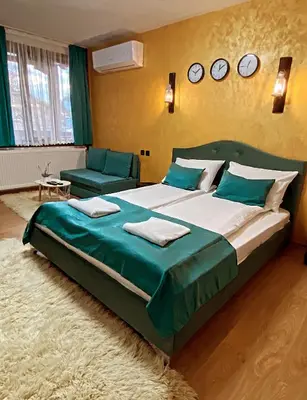 a bedroom with a large bed and a couch and clocks on the wall at Rooms in Leshten in Leshten