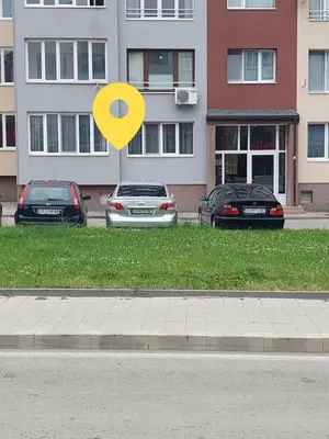 a yellow sign in the grass next to parked cars at Familia Apartments in Samokov