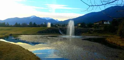 a fountain in a river with mountains in the background at ALL VIEW in Golf Resort in Razlog
