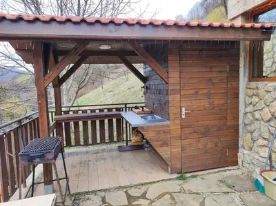 a wooden building with a grill on a deck at Терасите - Къща 2 in Ribarica