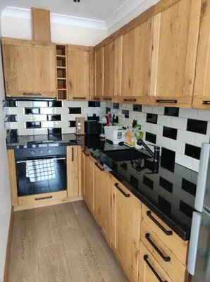a kitchen with wooden cabinets and black and white tiles at Терасите - Къща 3 in Ribarica