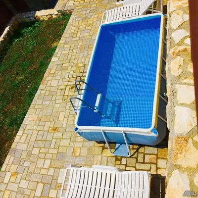 an overhead view of a blue swimming pool with two white benches at Терасите - Къща 4 in Ribarica