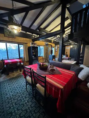 a dining room with a red table and a couch at СТАРАТА КЪЩА in Sovolyano