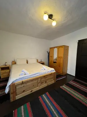a bedroom with a large wooden bed and a ceiling at СТАРАТА КЪЩА in Sovolyano