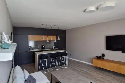 a kitchen with bar stools and a living room at Mila's Cozy 1 Bedroom Apartment in Sofia