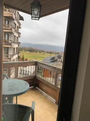 a balcony with a table and a view of a field at Private Apartment Pirin Golf Club with Lake View in Razlog