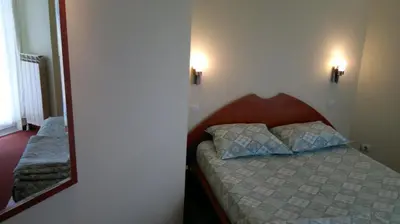 a small bedroom with a bed and a mirror at Classic Hotel in Sofia