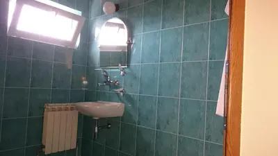 a green tiled bathroom with a sink and a window at Classic Hotel in Sofia